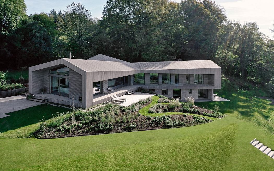 A modern, two-story home with a sleek, geometric design, surrounded by lush greenery.