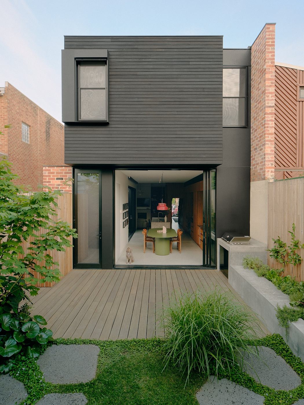 Contemporary exterior with sleek gray siding, large windows, and an inviting wooden deck overlooking a lush garden.