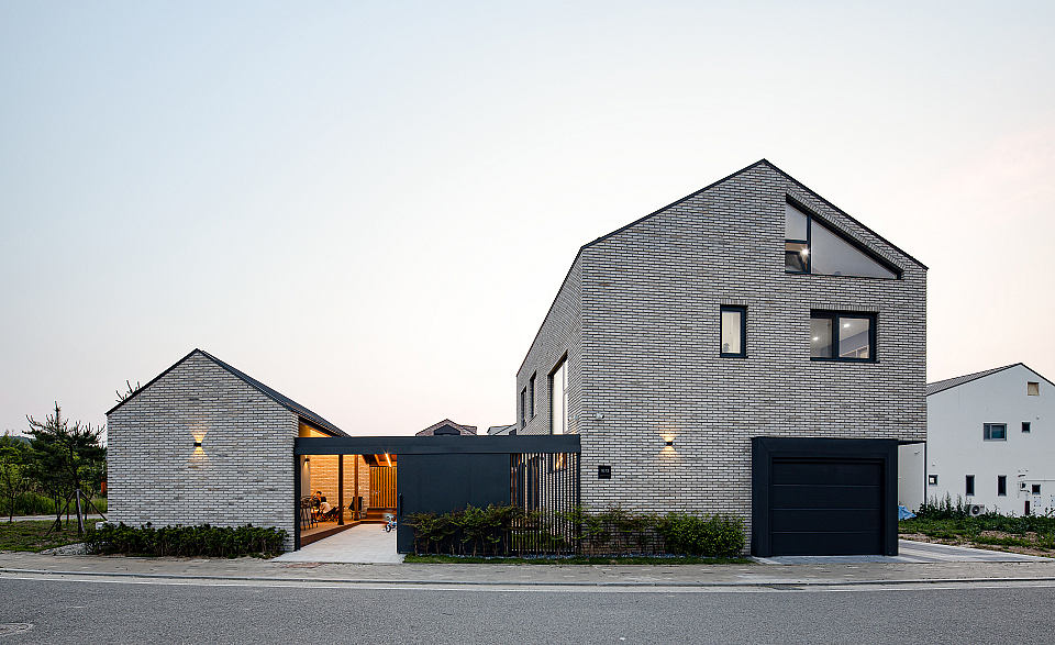 Modern brick facade with gabled roof, large windows, and a garage door. Minimalist exterior design.