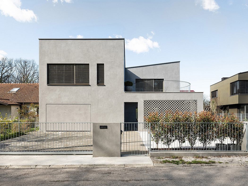A modern, minimalist building with geometric shapes, concrete walls, and decorative metal fencing.