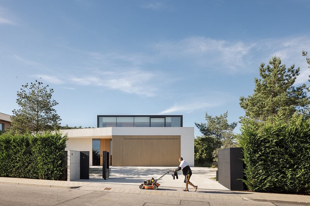 A modern, minimalist house with clean lines, wood accents, and expansive windows amid lush greenery.