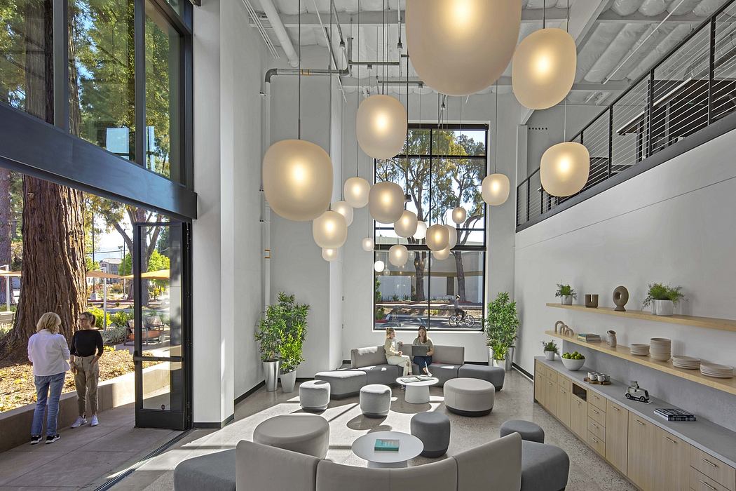 Modern, open-plan office space with pendant lighting, minimalist furniture, and expansive windows overlooking nature.