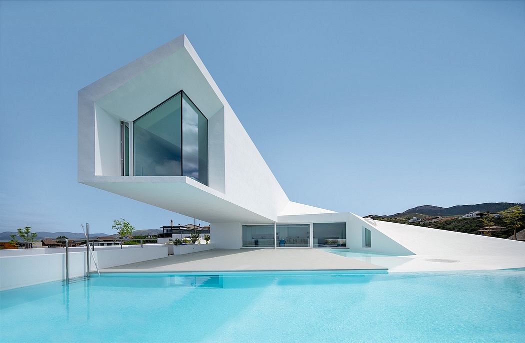 Striking modern architecture with a sleek, angular design and large glass windows overlooking a pool.