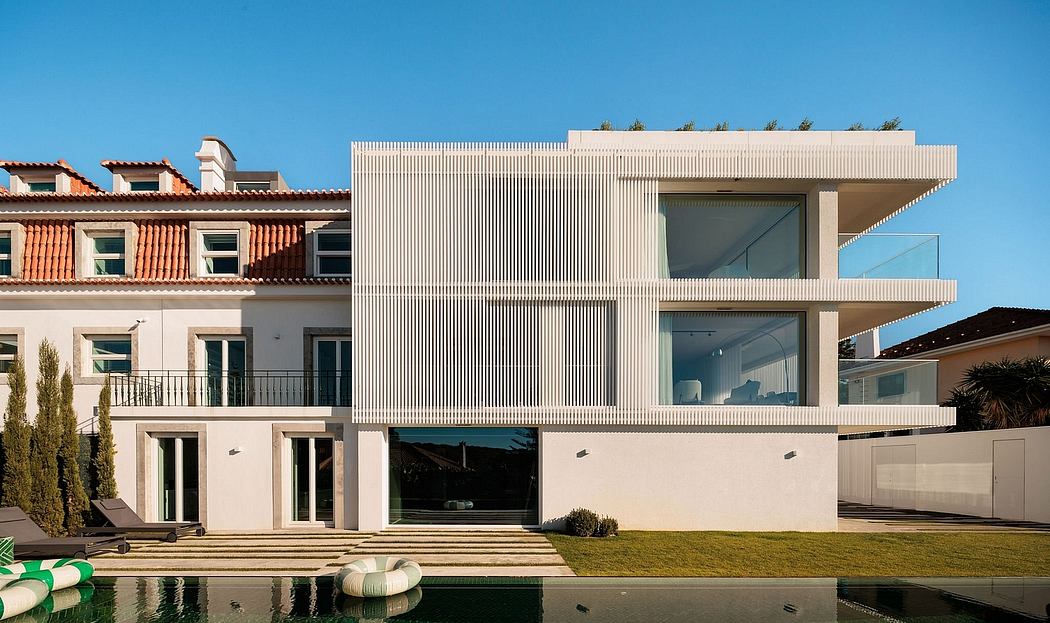 Striking modern architecture with clean lines, large windows, and a balcony overlooking a pool.