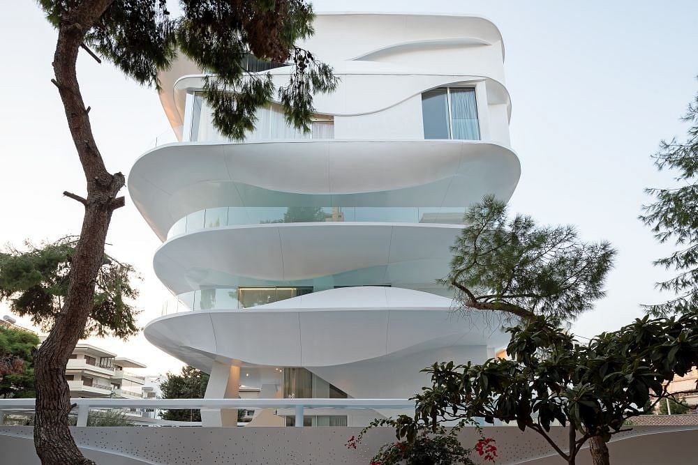 Striking contemporary architecture with curved, layered facade and lush greenery.