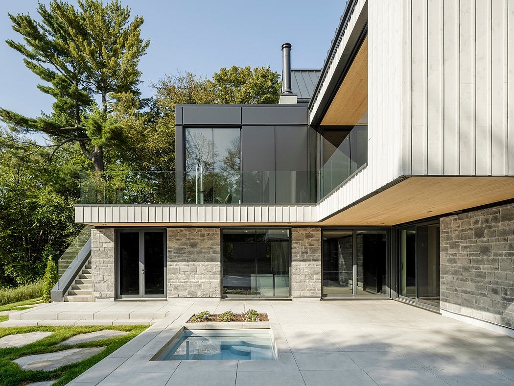 Modern residential building with glass walls, stone exterior, and a small pool in the courtyard.