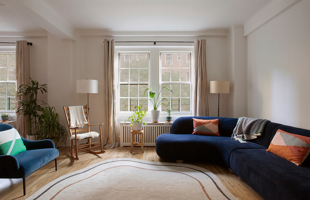 Cozy living room with large windows, plush navy sofa, and potted plants accenting the space.