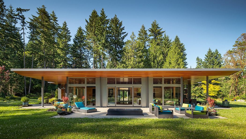 Sleek, modern home with large glass windows and wooden beams nestled in lush greenery.