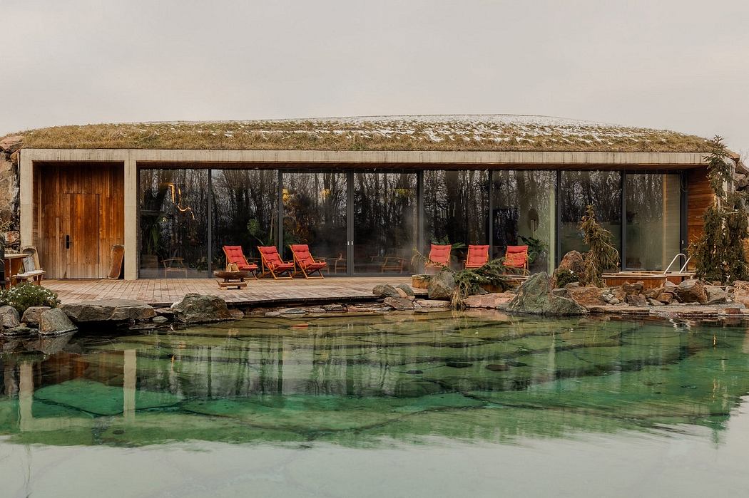 A contemporary glass-walled structure with wooden roof elements, nestled by a scenic pool.