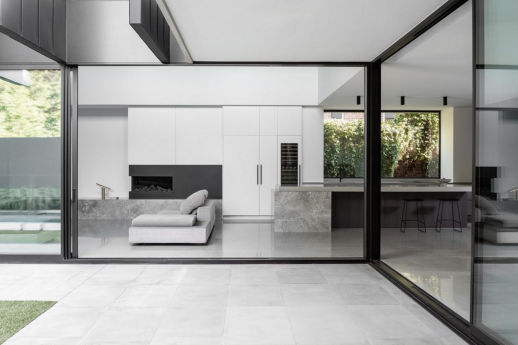 Modern minimalist interior with sleek black-framed glass walls, open-concept layout, and integrated kitchen.