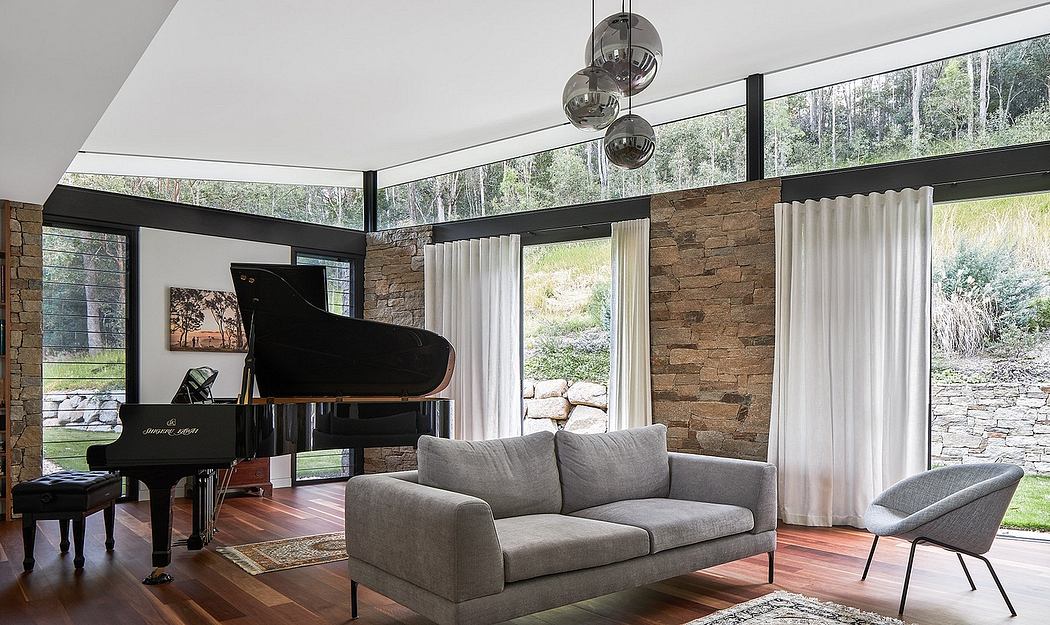 Spacious modern living room with grand piano, stone walls, and floor-to-ceiling windows.