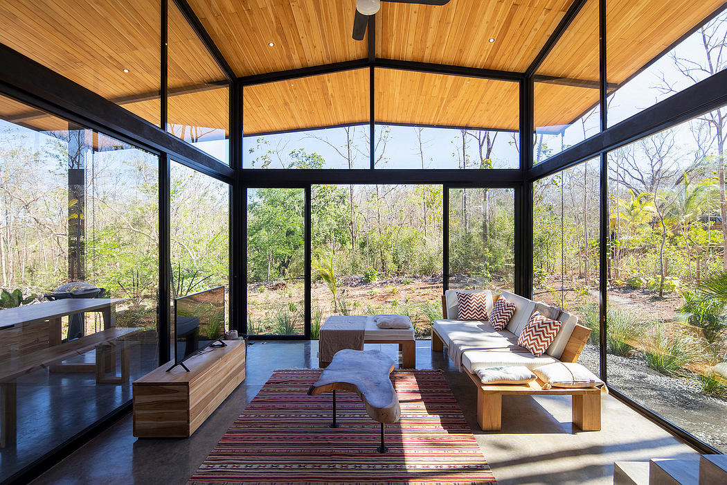 A modern, glass-enclosed patio with wood-paneled ceilings and rustic, cozy furnishings.