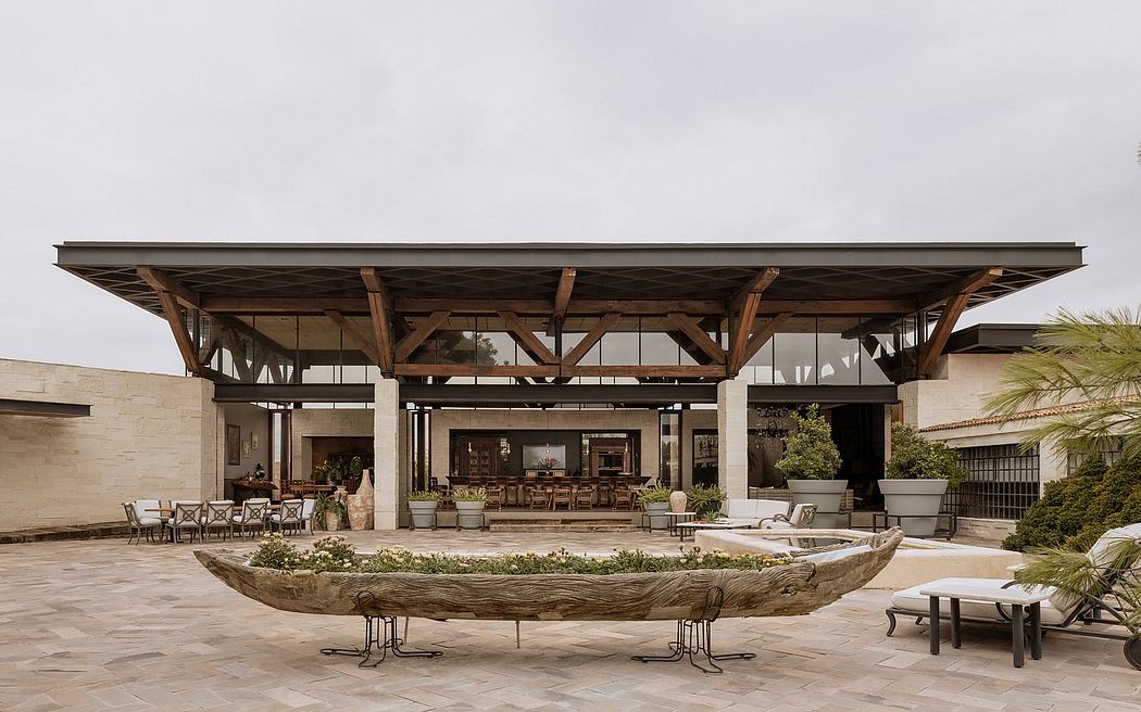 Expansive wooden structure with glass walls, outdoor seating, and landscaping elements.