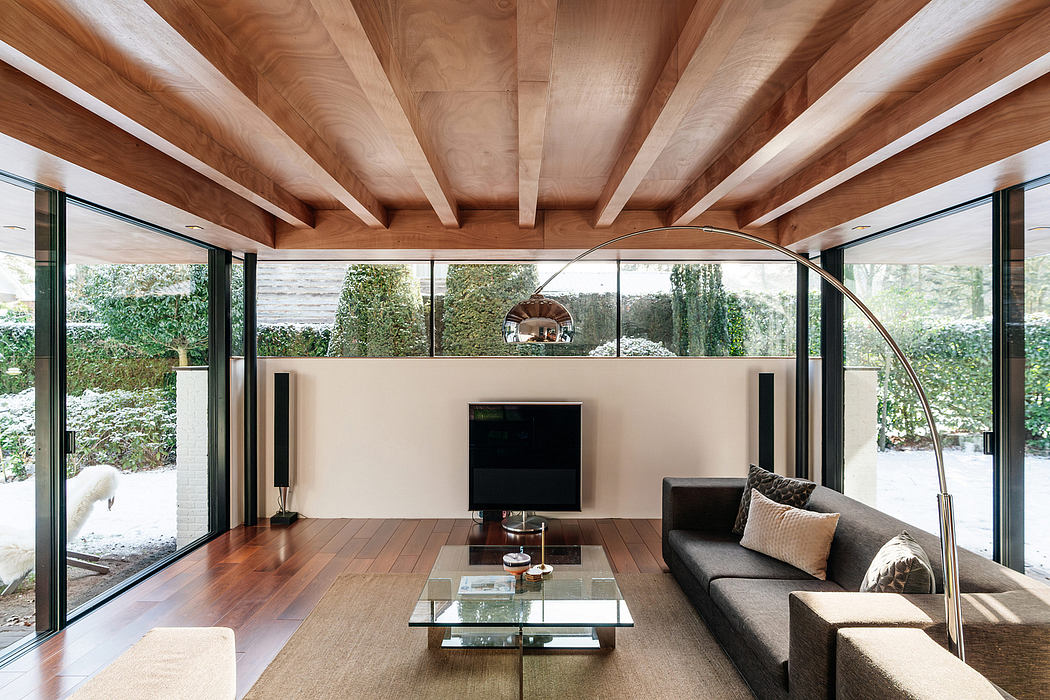 Modern open-plan living space with wooden beams, glass walls, and a glass coffee table.