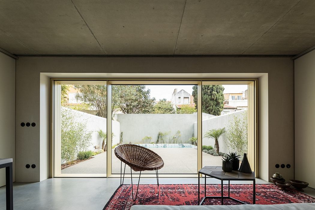 Minimalist living room with floor-to-ceiling windows overlooking a lush outdoor patio.
