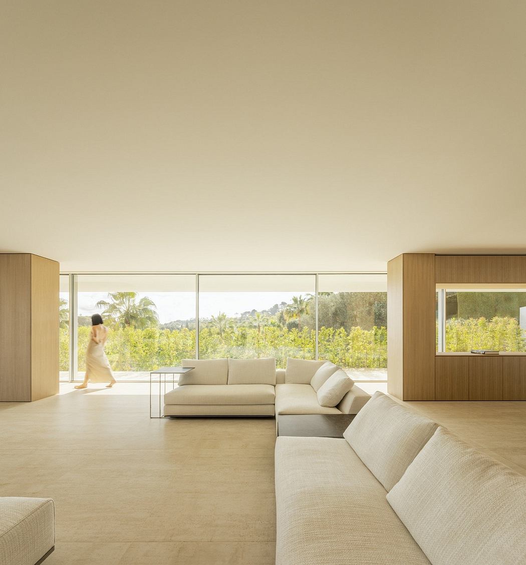 Spacious living room with large windows overlooking lush green landscape, modern furnishings.