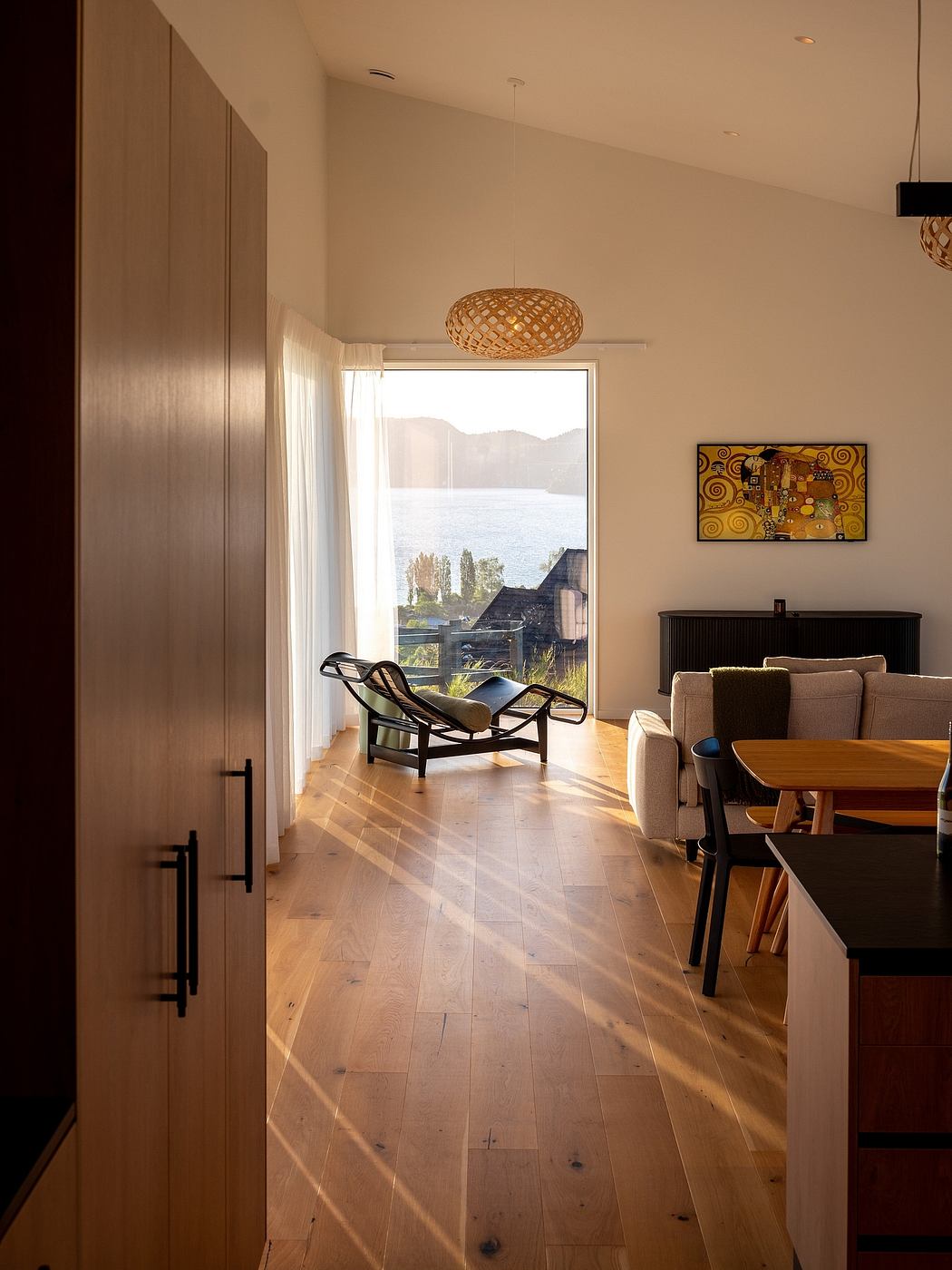 Spacious, modern living area with wooden floors, artwork, and a scenic window view.