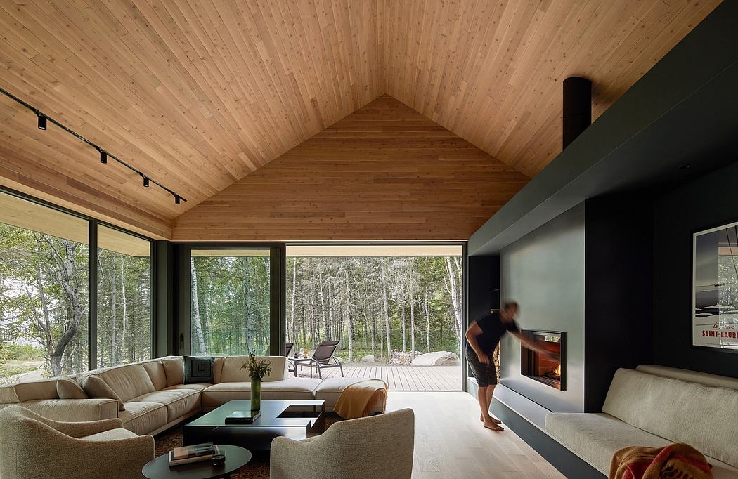 A cozy, modern cabin interior with wooden walls, large windows, and a fireplace.