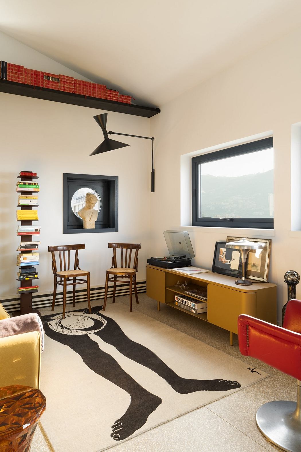 Minimalist living room with vintage furniture, modern lighting, and artistic rug.