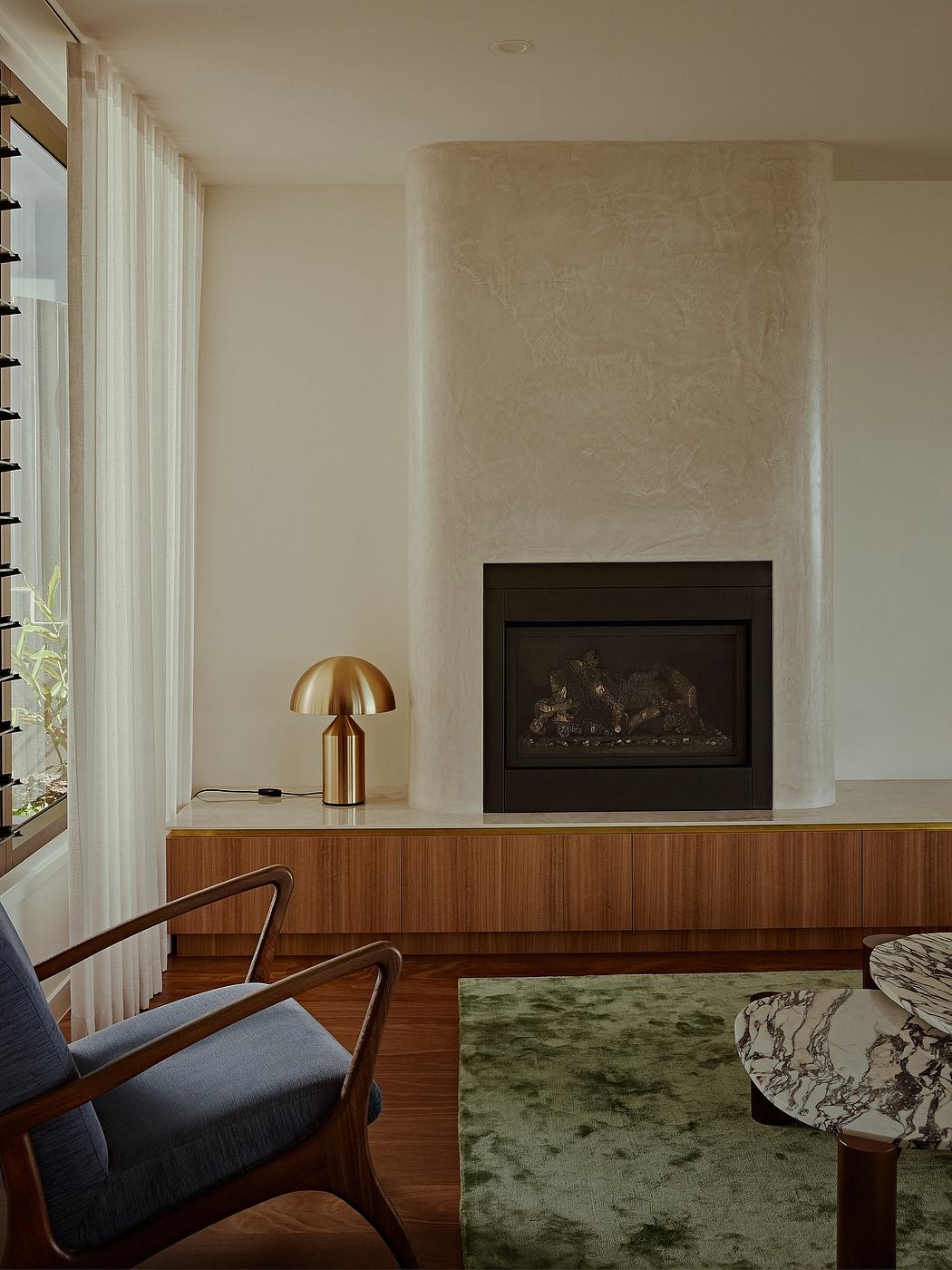 Modern living room with minimalist fireplace, wood accents, and brass lighting.
