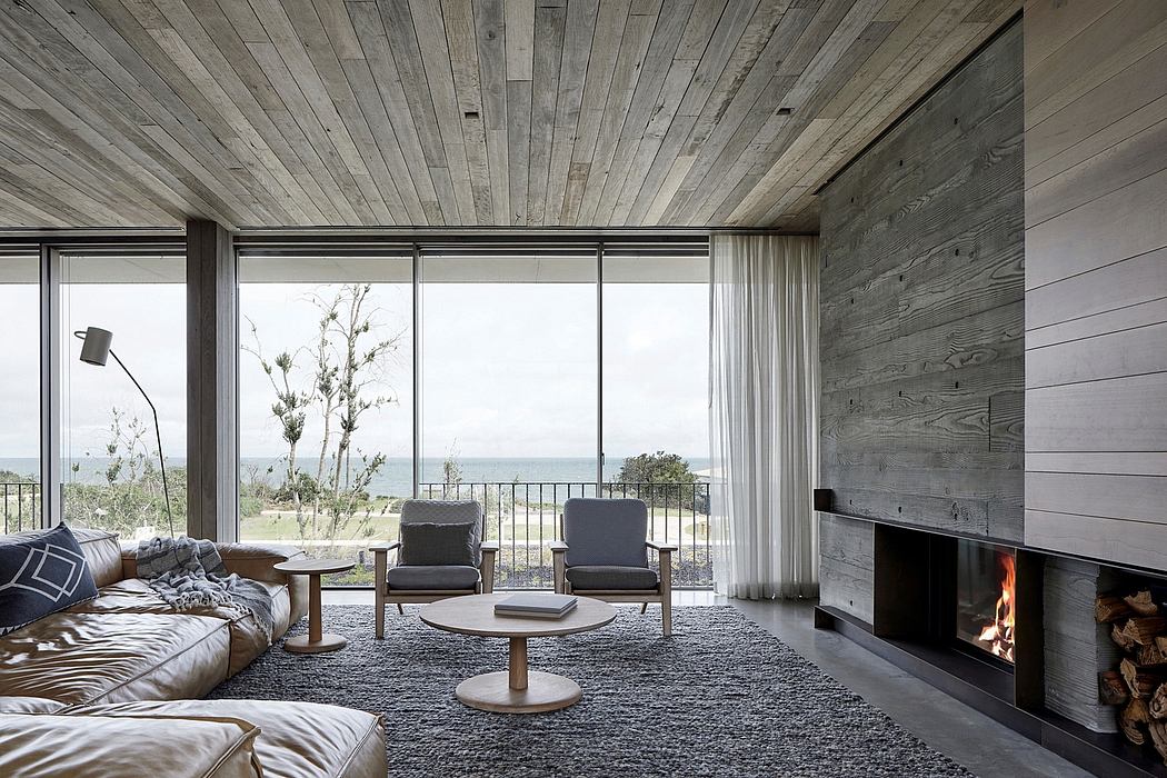 Spacious living room with wooden walls, large windows, fireplace, and comfortable seating.