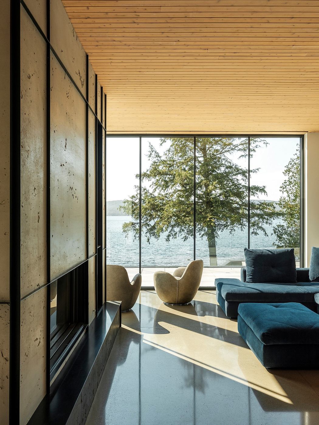 Spacious modern living room with floor-to-ceiling windows overlooking a scenic lakefront.