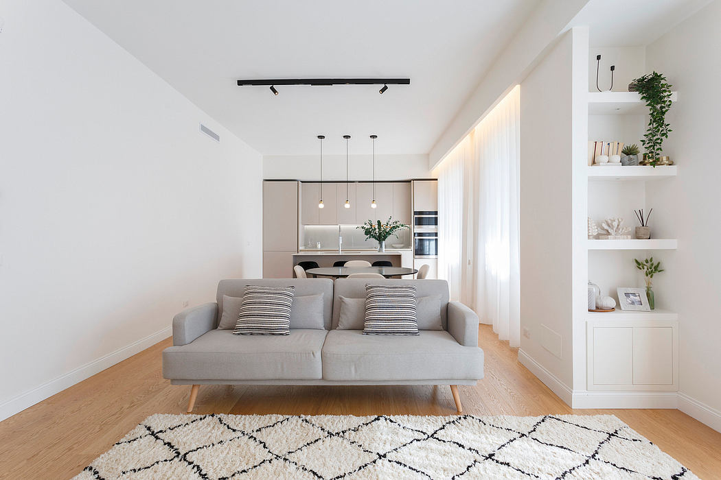 Minimalist living room with gray sofa, white shelving, and pendant lighting over wooden floors.