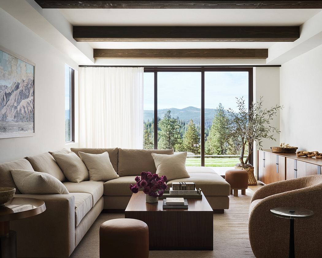 An airy and cozy living room with a large window overlooking a lush, forested landscape.