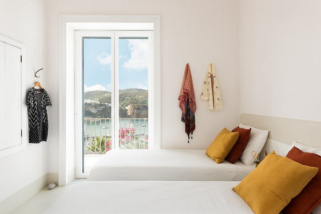 A cozy bedroom with a panoramic window overlooking a scenic landscape. Vibrant textiles and neutral decor create a serene ambiance.