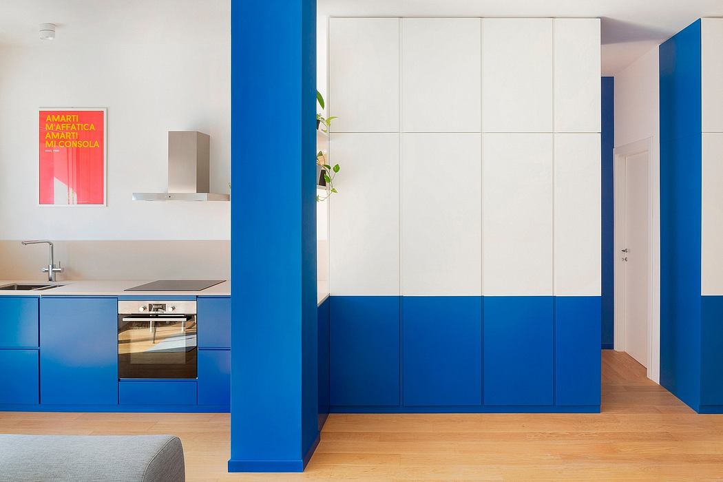 Vibrant blue kitchen cabinetry, white built-in wardrobes, and a bold graphic artwork create a modern interior.