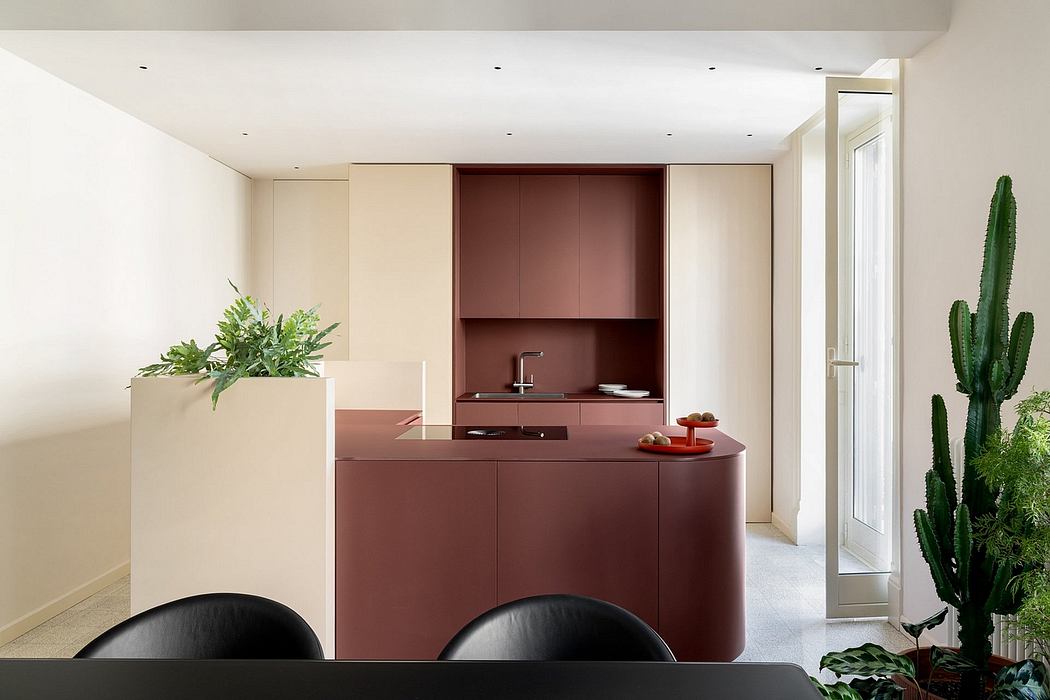 A modern, minimalist kitchen with clean lines, red-brown cabinetry, and potted plants.