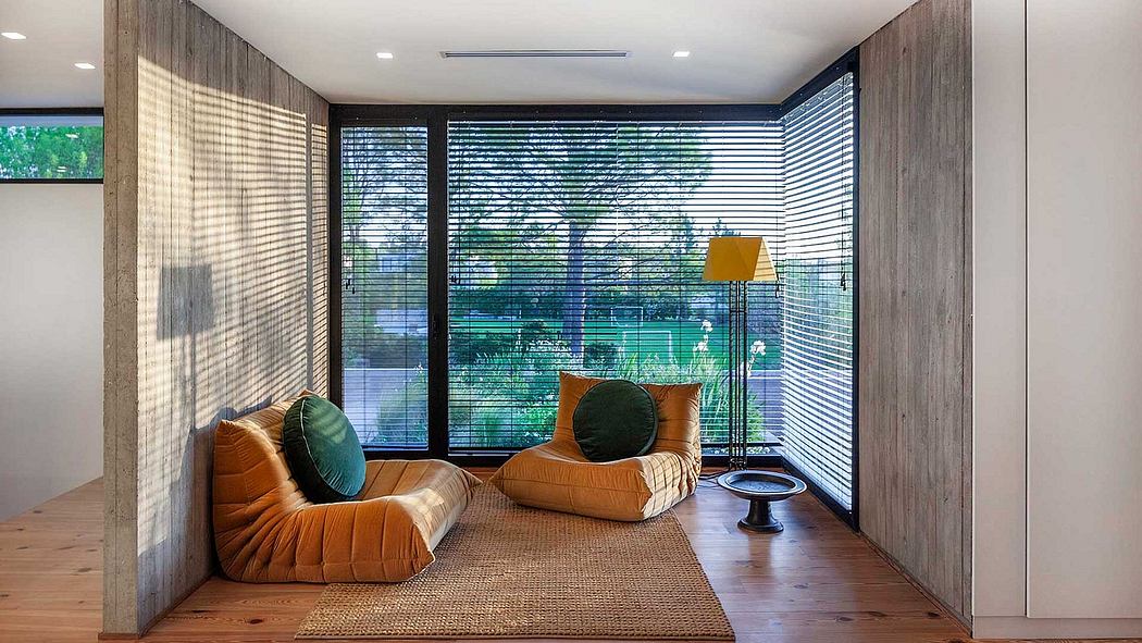 Modern living room with cozy orange sofas, wooden paneling, and large windows offering scenic views.