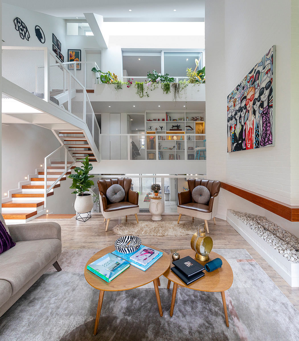 Modern open-plan living space with stylish stairs, art, and cozy furnishings.