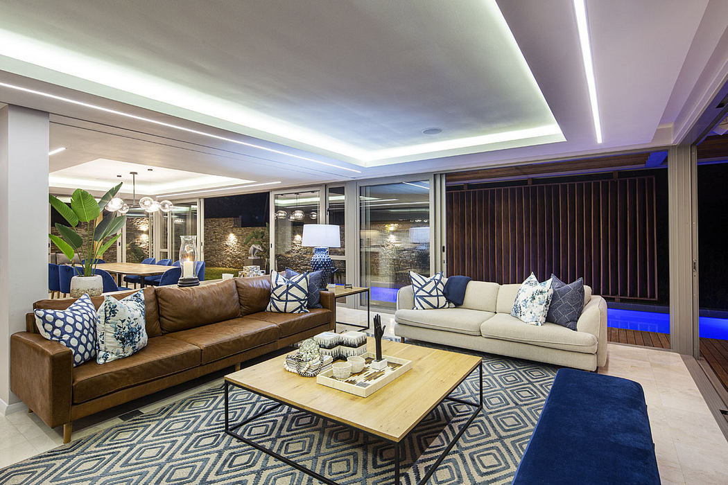 Spacious modern living room with stylish furniture, lighting, and patterned rug.