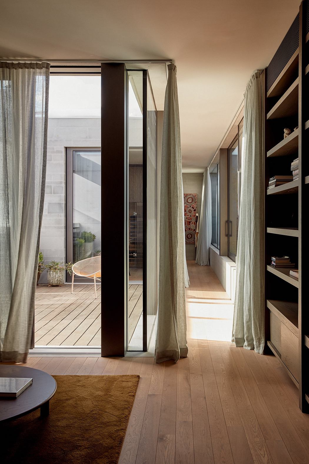 Minimalist hallway with floor-to-ceiling windows, wooden floors, and built-in shelving.