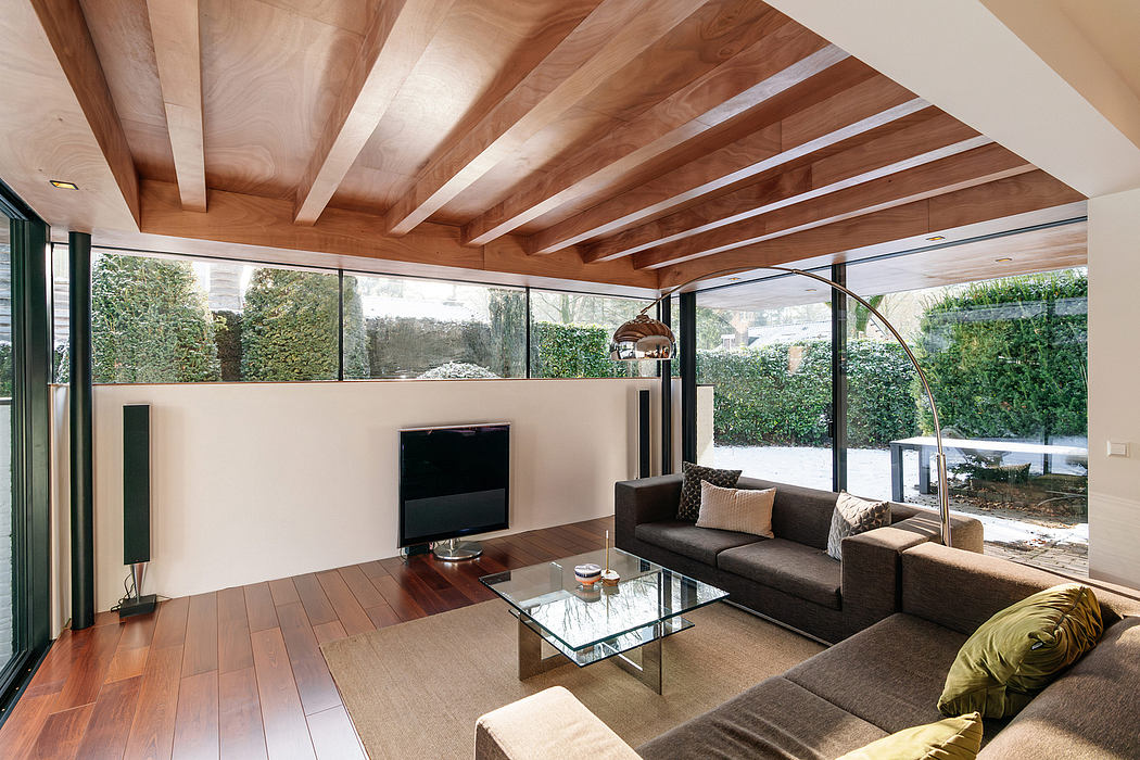 Spacious modern living room with wood-paneled ceiling, glass walls, and a sleek sofa arrangement.