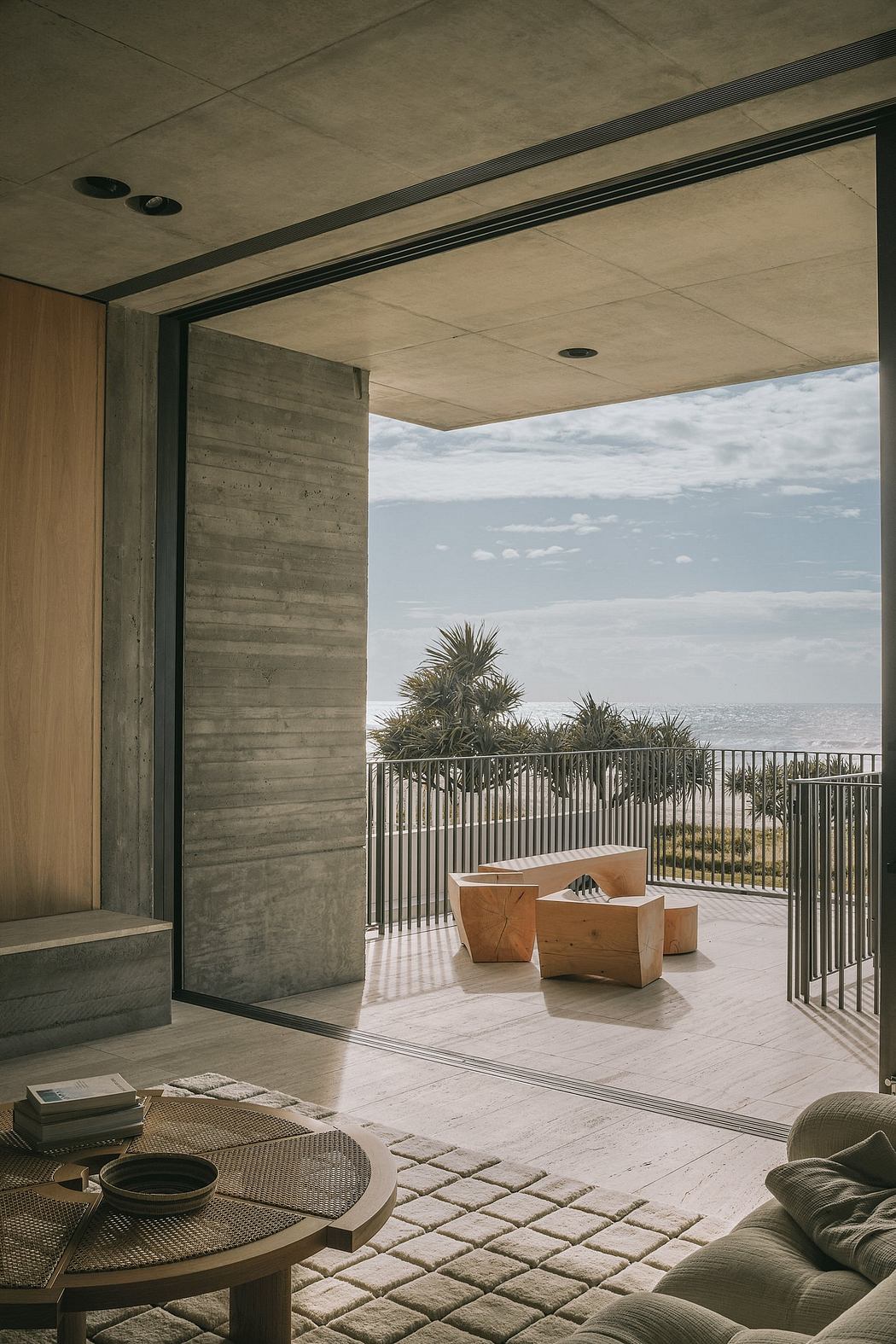 Concrete walls, glass doors, and balcony with palm trees overlooking the ocean.
