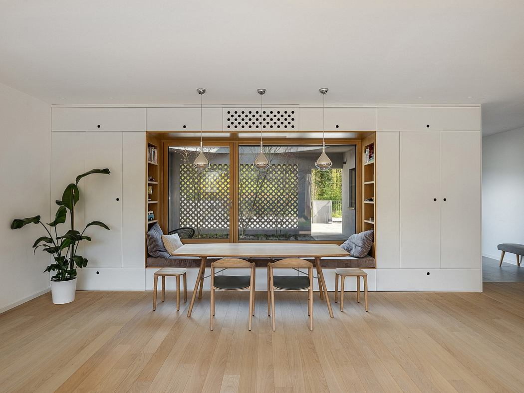 Minimalist dining area with wooden furnishings, built-in seating, and geometric window screens.