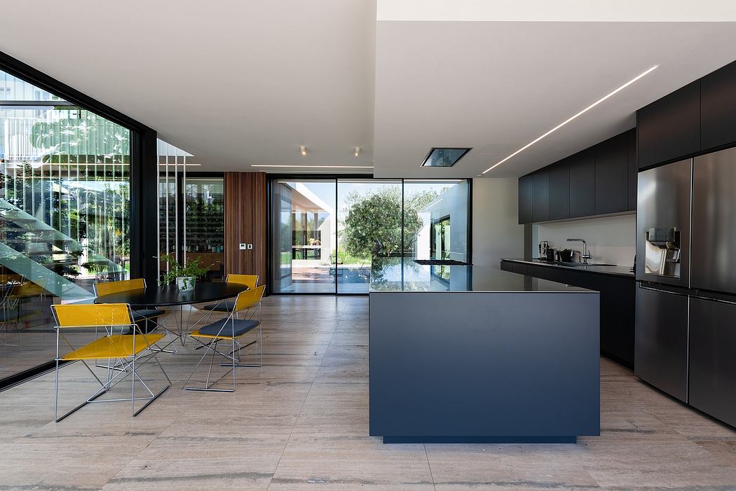 Sleek, modern kitchen with black cabinetry, island, and floor-to-ceiling windows overlooking a pool.