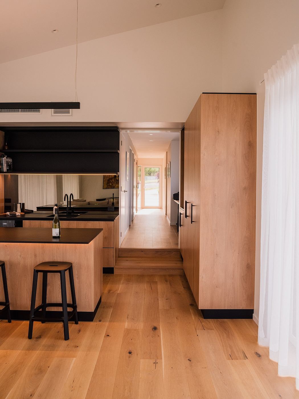 Modern and minimalist kitchen with sleek wooden cabinetry, dark accents, and a warm, inviting atmosphere.