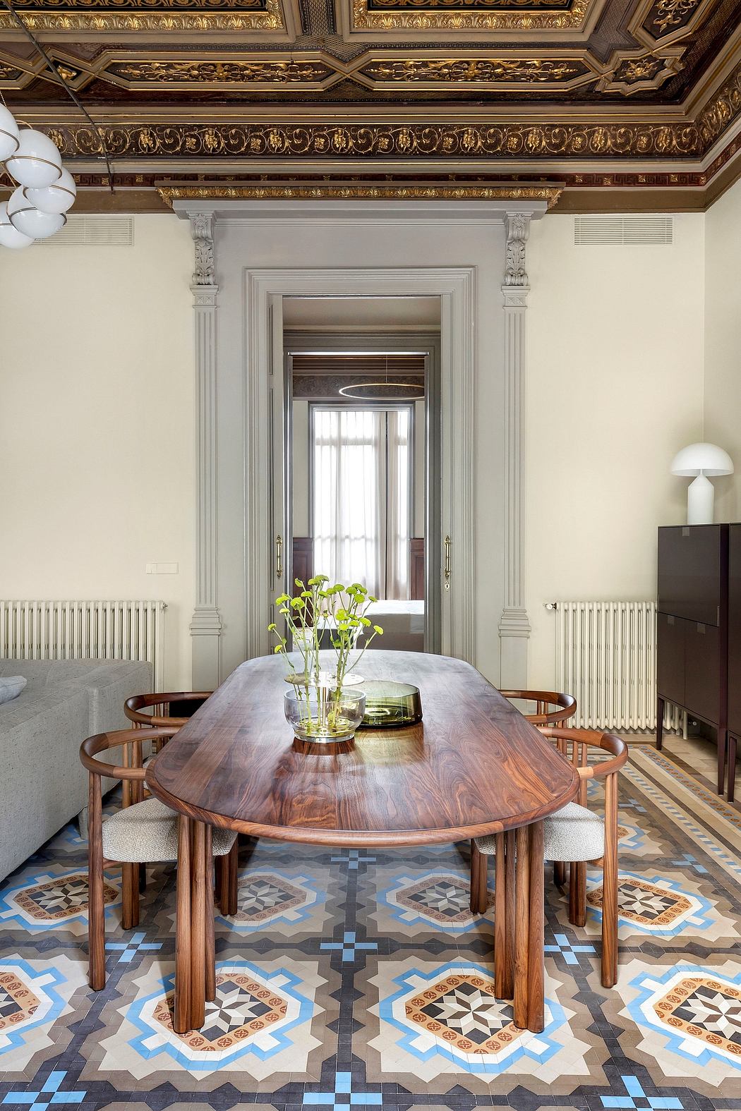 Ornate vintage-style ceiling, wooden dining table, patterned tile floor, and elegant decor.