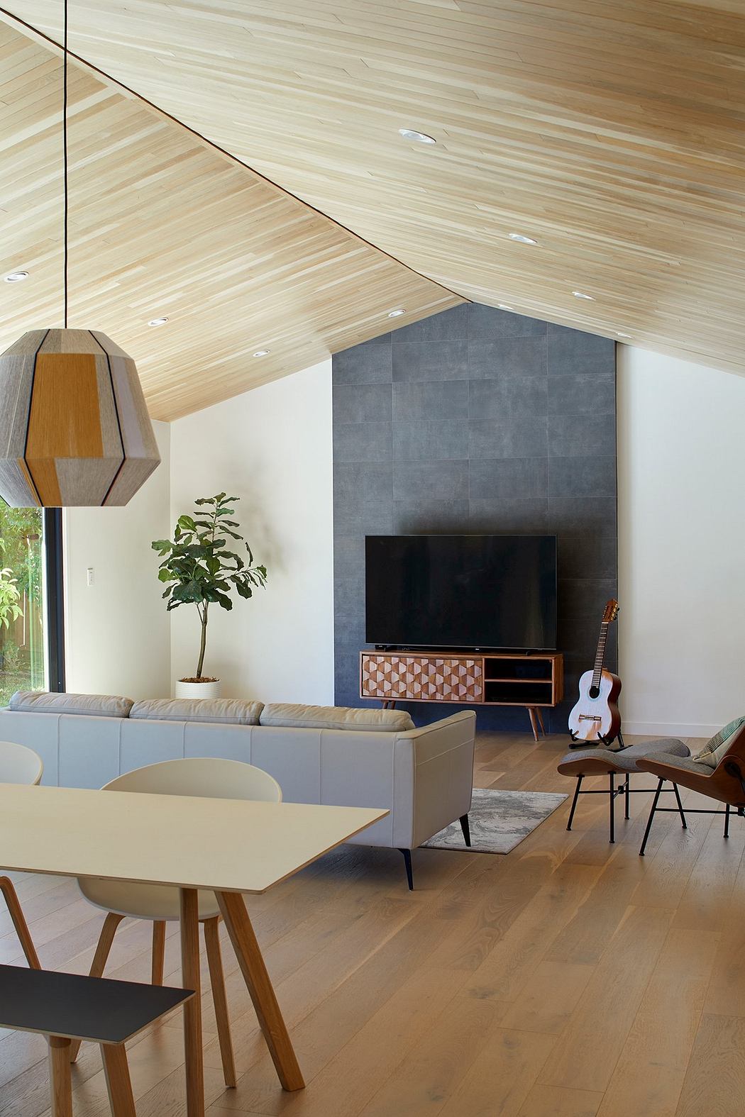 Warm wood ceiling, textured concrete wall, sleek furniture, and a touch of nature.