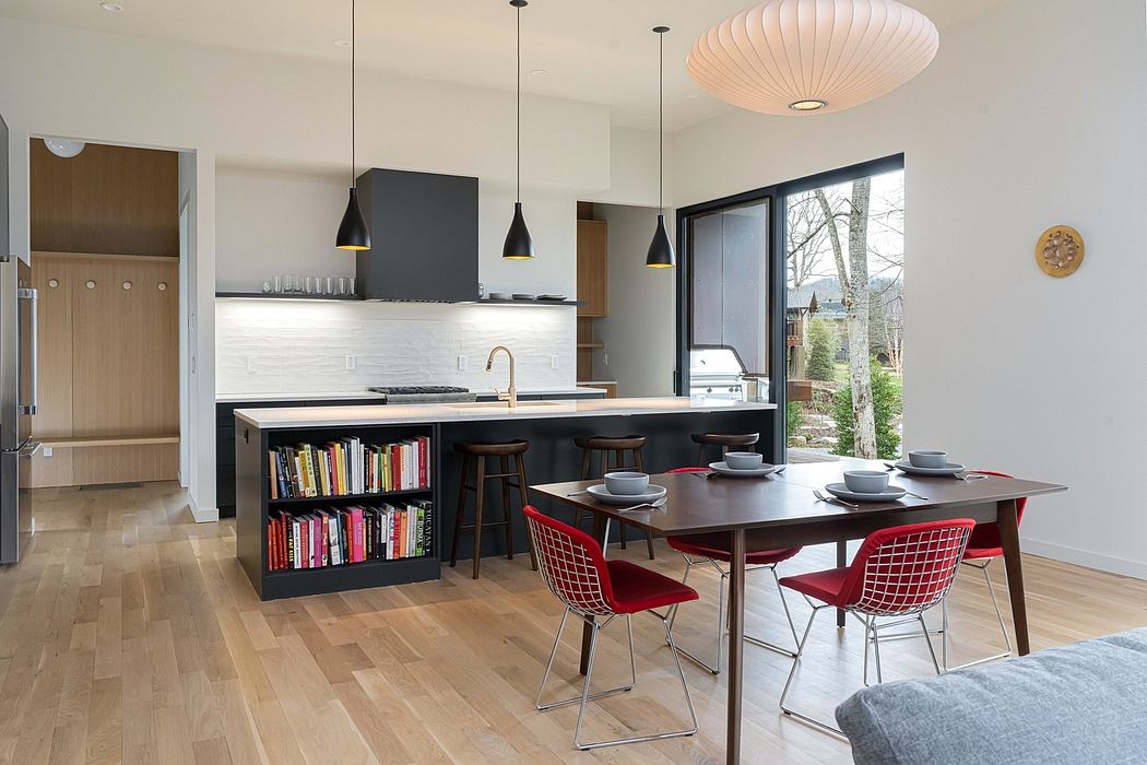 Spacious modern kitchen and dining room with geometric lighting, wood accents, and bookshelf.