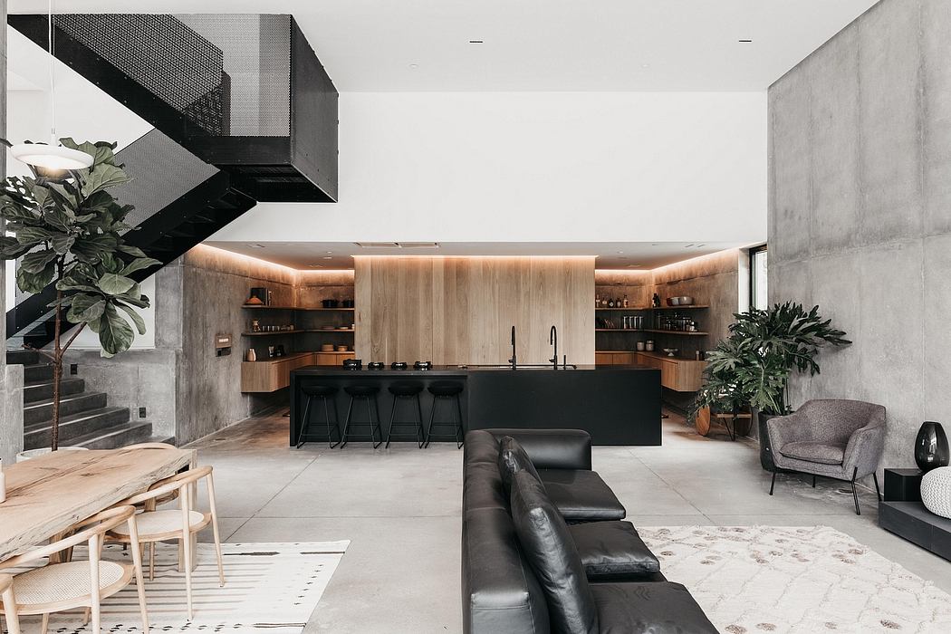 Modern, open-concept kitchen and living space with concrete walls, wood accents, and black furnishings.