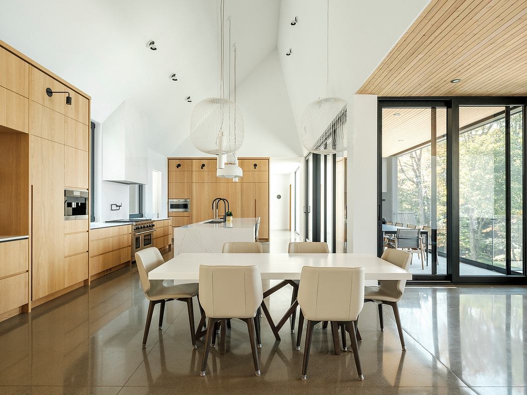 Spacious, modern kitchen and dining area with sleek wood cabinetry, pendant lights.