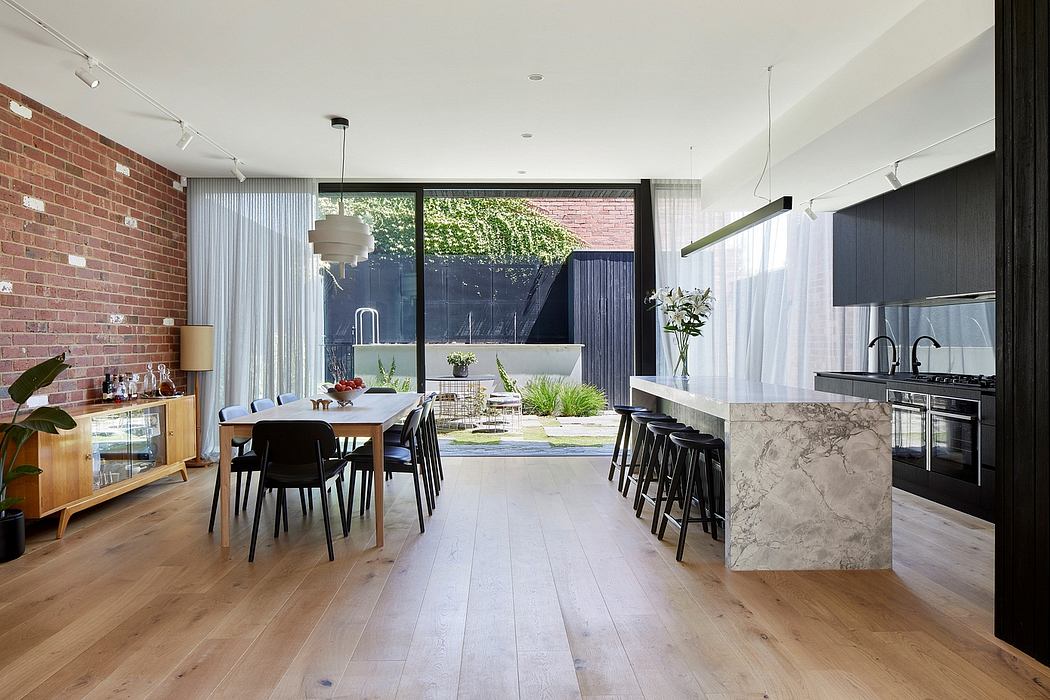 Bright, modern kitchen and dining space with brick walls, wooden floors, and large window.