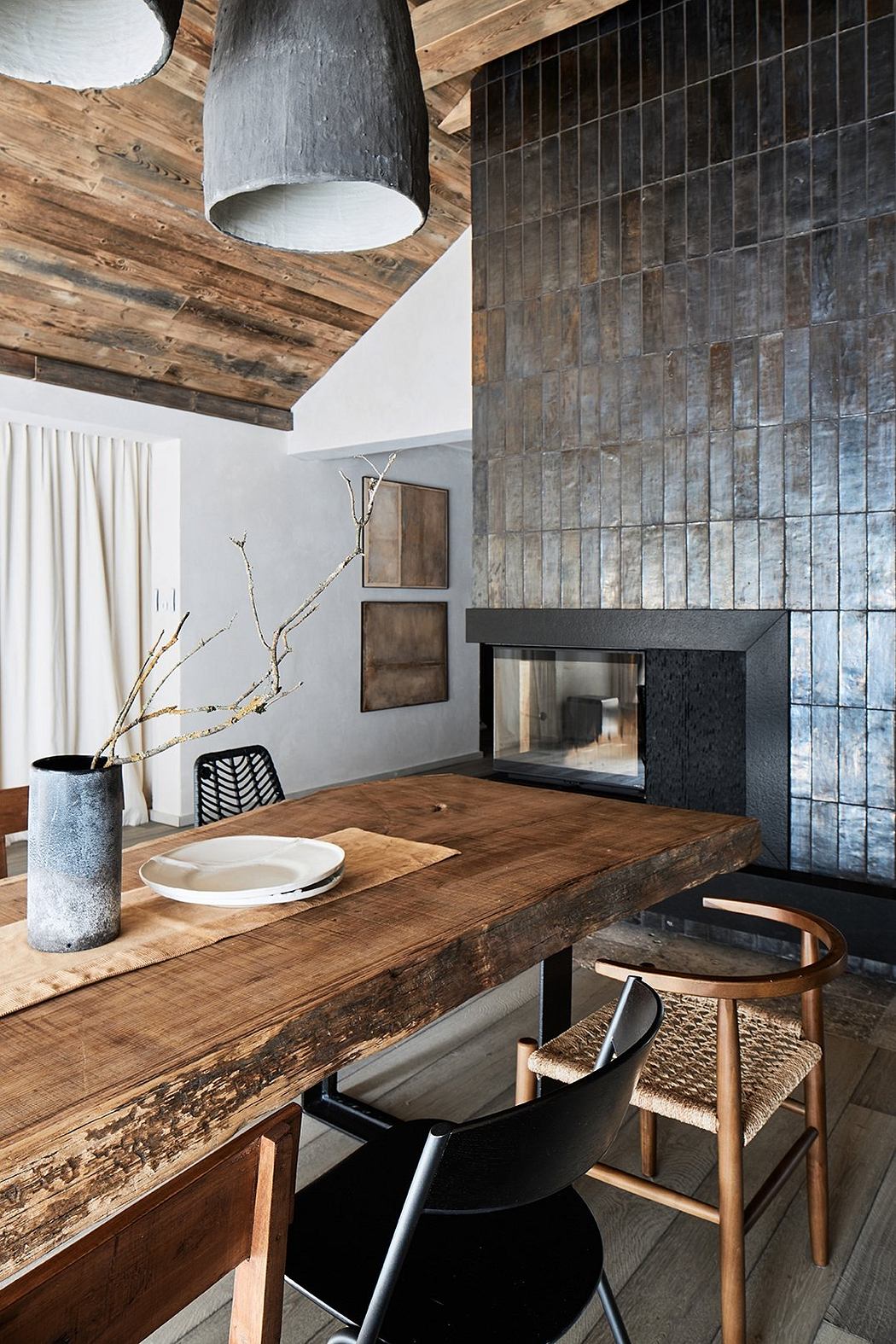 Rustic wooden ceiling, textured stone wall, minimalist dining area with wooden table and chairs.