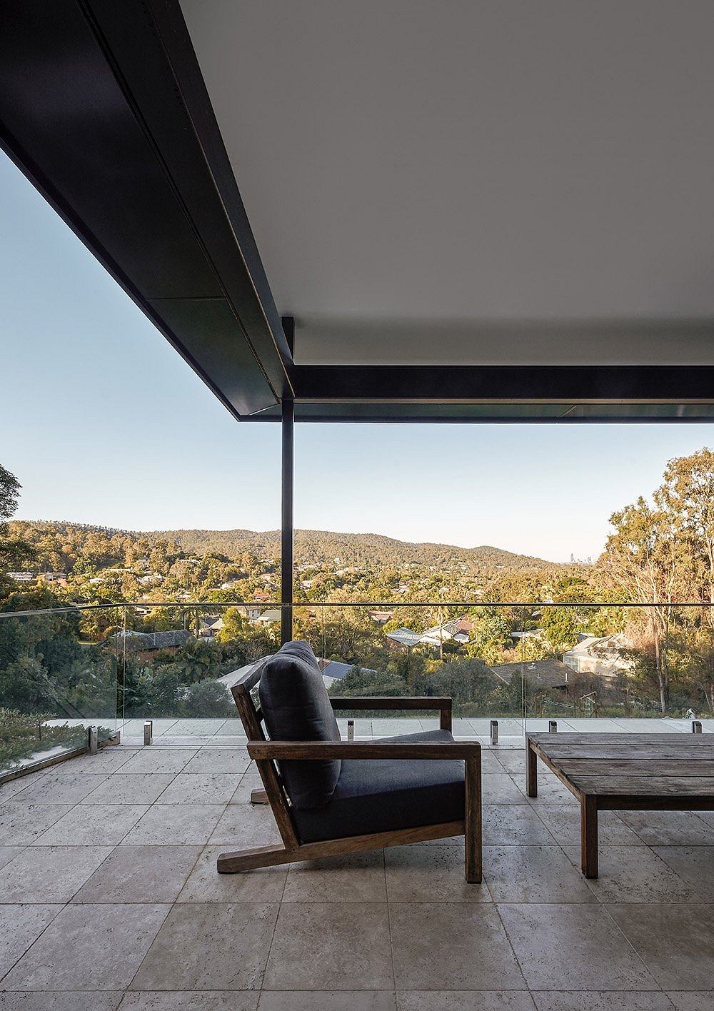 A modern outdoor patio with sleek wooden furniture and a panoramic view of rolling hills.