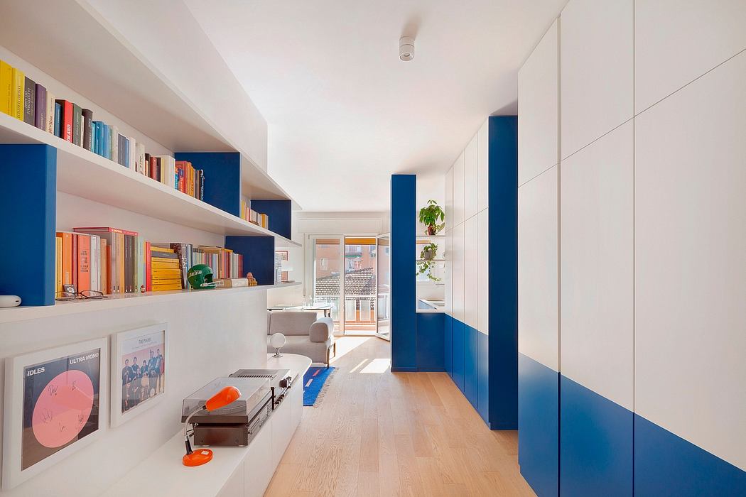 A modern, minimalist hallway with white walls, bright blue accents, and built-in bookshelves.