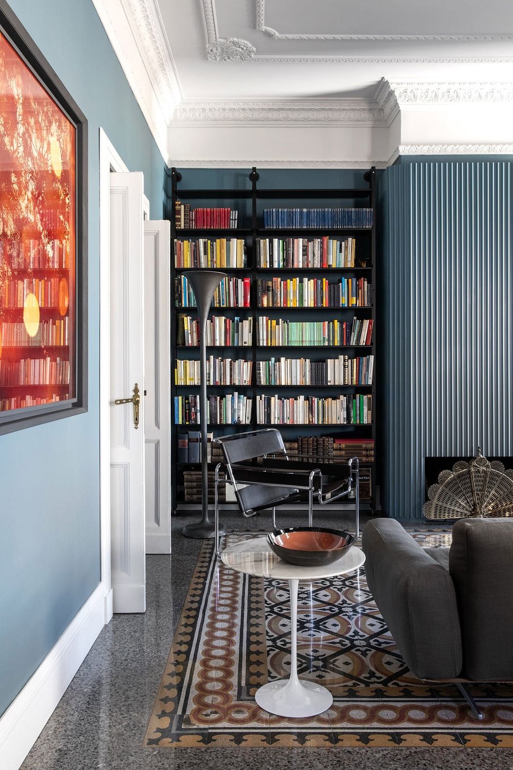 A cozy library nook with built-in bookshelves, a patterned rug, and a mid-century modern chair.
